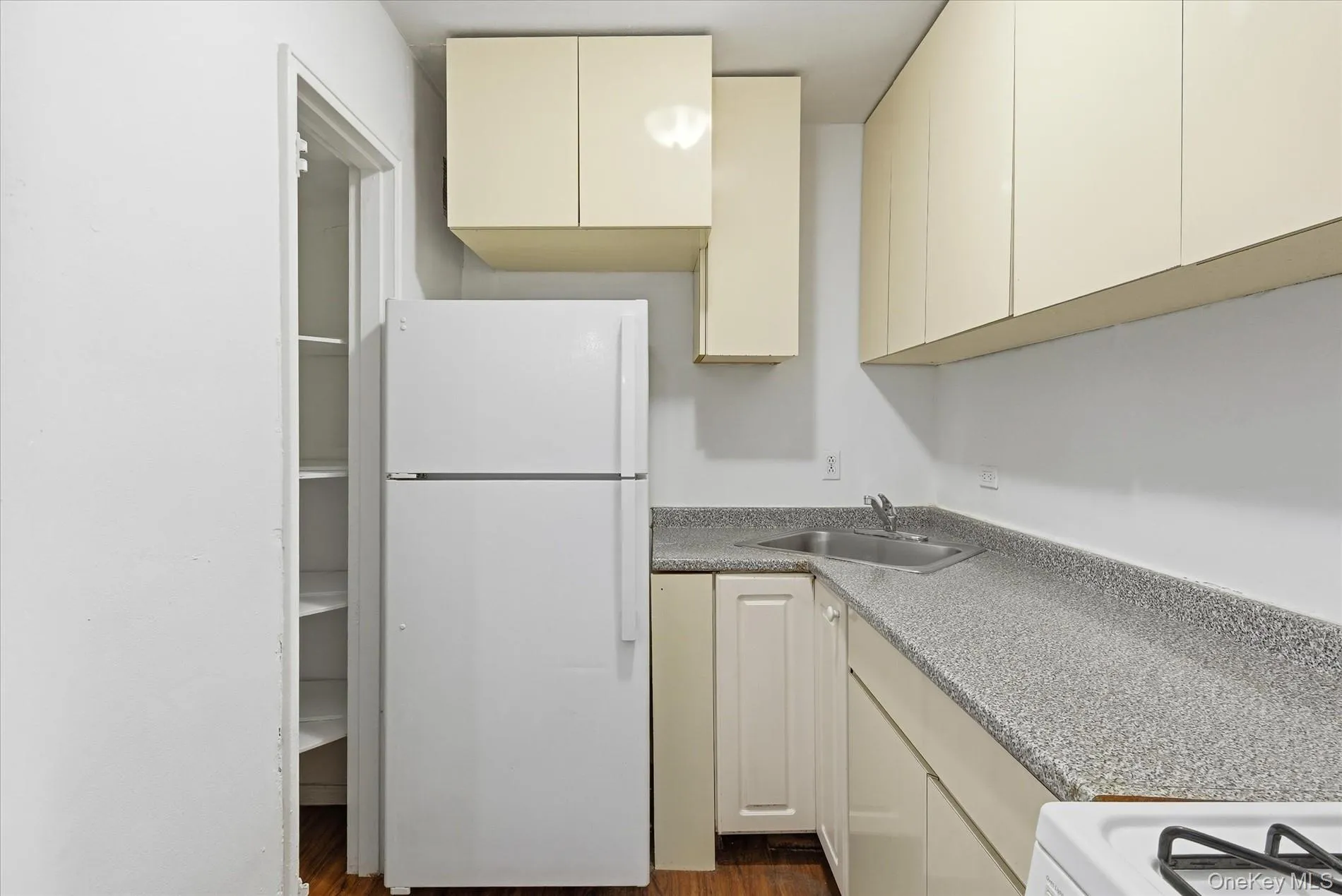 Kitchen with white appliances, cream cabinets, and dark wood-type flooring Kitchen with white appliances, cream cabinets, and dark wood-type flooring