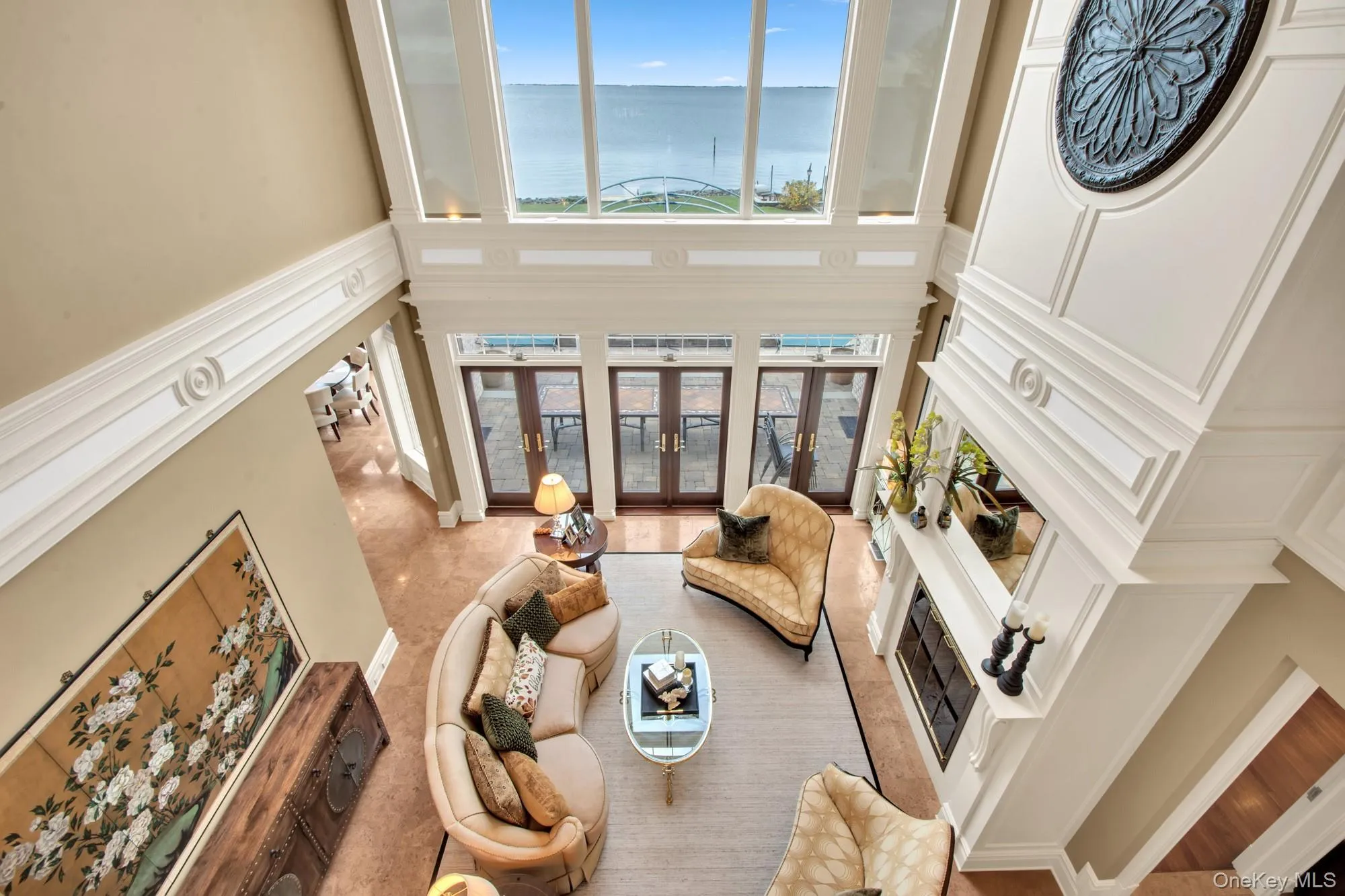 Living room featuring plenty of natural light, a water view, a decorative wall, and a high ceiling Living room featuring plenty of natural light, a water view, a decorative wall, and a high ceiling