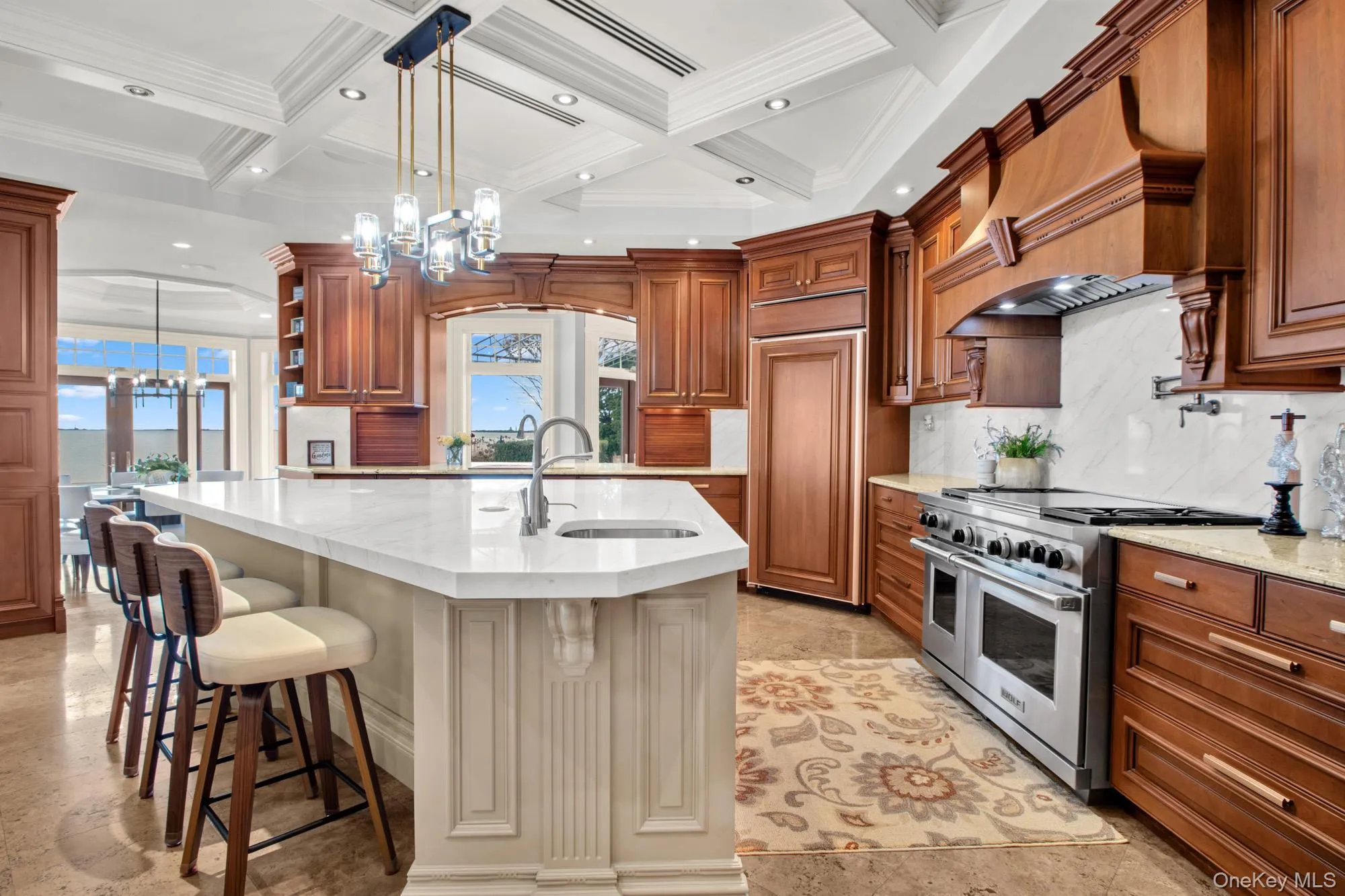 Kitchen with pendant lighting, a chandelier, high end appliances, open shelves, and light stone counters Kitchen with pendant lighting, a chandelier, high end appliances, open shelves, and light stone counters