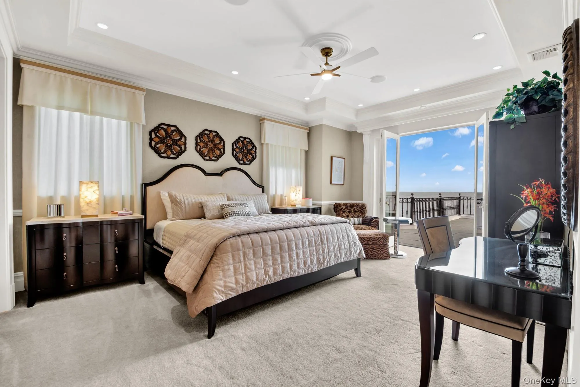 Bedroom featuring multiple windows, light colored carpet, a tray ceiling, access to exterior, and crown molding Bedroom featuring multiple windows, light colored carpet, a tray ceiling, access to exterior, and crown molding