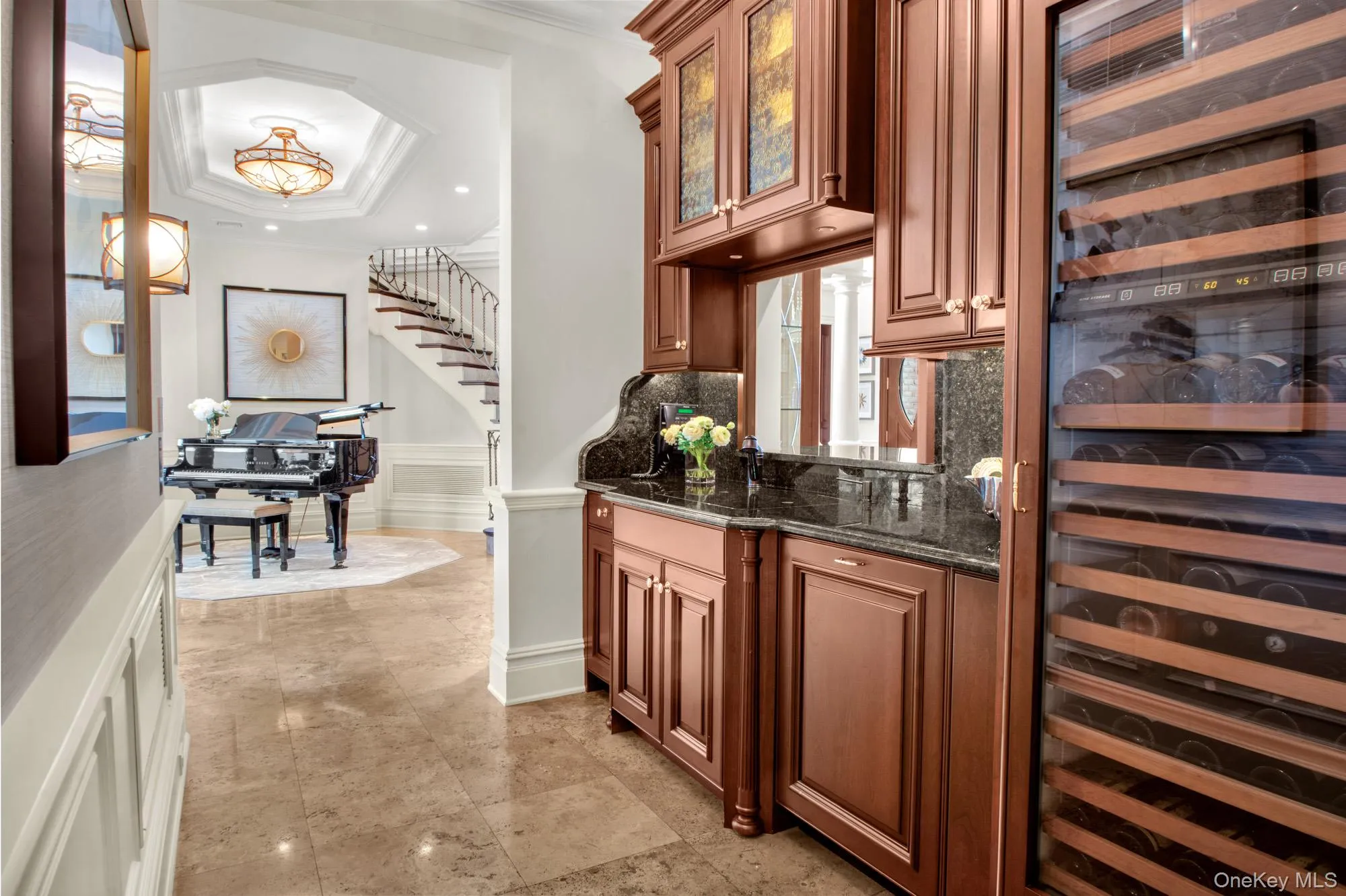 Bar area featuring wine cooler, ornamental molding, dark stone countertops, a raised ceiling, and glass insert cabinets Bar area featuring wine cooler, ornamental molding, dark stone countertops, a raised ceiling, and glass insert cabinets