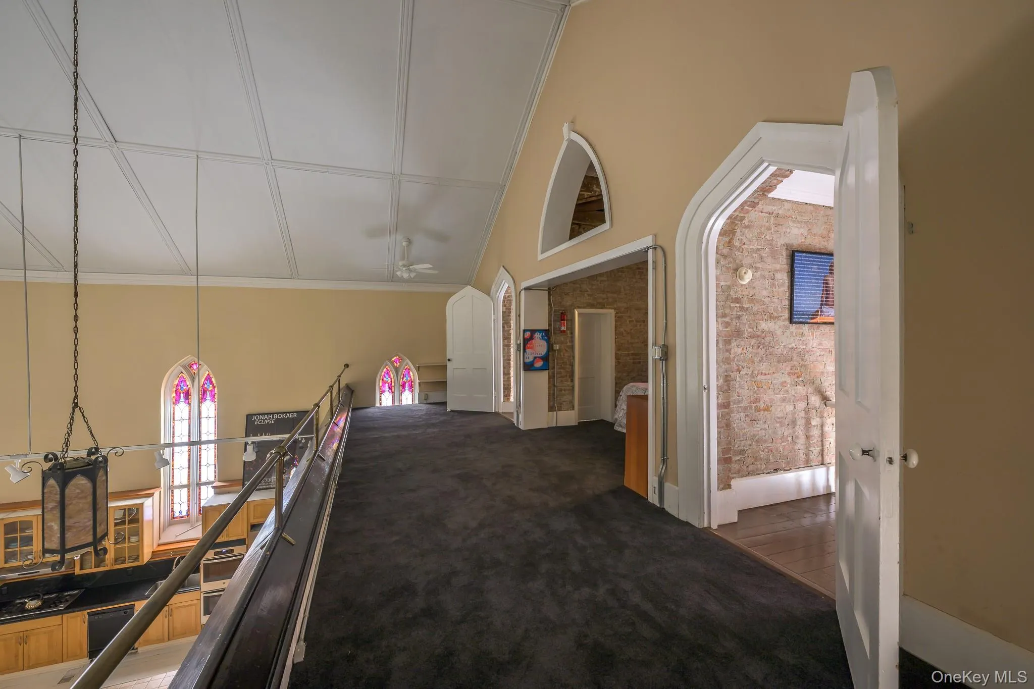 Hallway with carpet floors, lofted ceiling, an upstairs landing, and ornamental molding Hallway with carpet floors, lofted ceiling, an upstairs landing, and ornamental molding