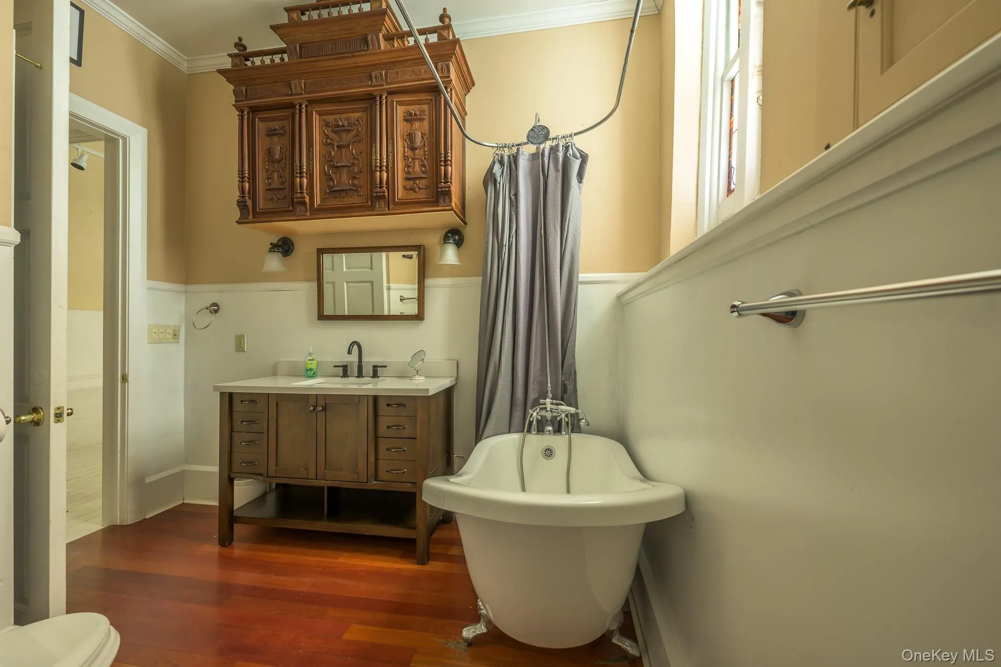 Bathroom with vanity, a soaking tub, crown molding, dark wood-type flooring, and curtained shower Bathroom with vanity, a soaking tub, crown molding, dark wood-type flooring, and curtained shower