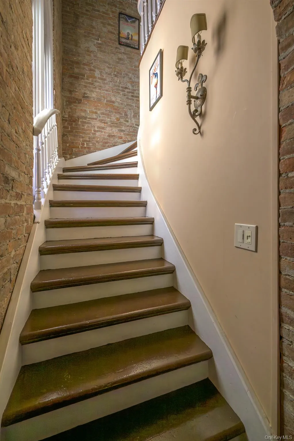 Stairway featuring brick wall and a high ceiling Stairway featuring brick wall and a high ceiling