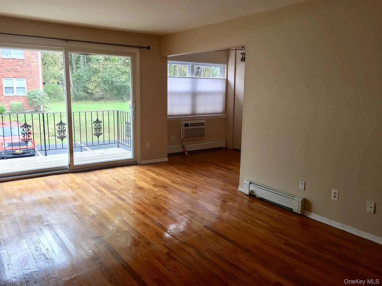 Unfurnished room featuring hardwood / wood-style floors, a baseboard heating unit, and a wall unit AC Unfurnished room featuring hardwood / wood-style floors, a baseboard heating unit, and a wall unit AC