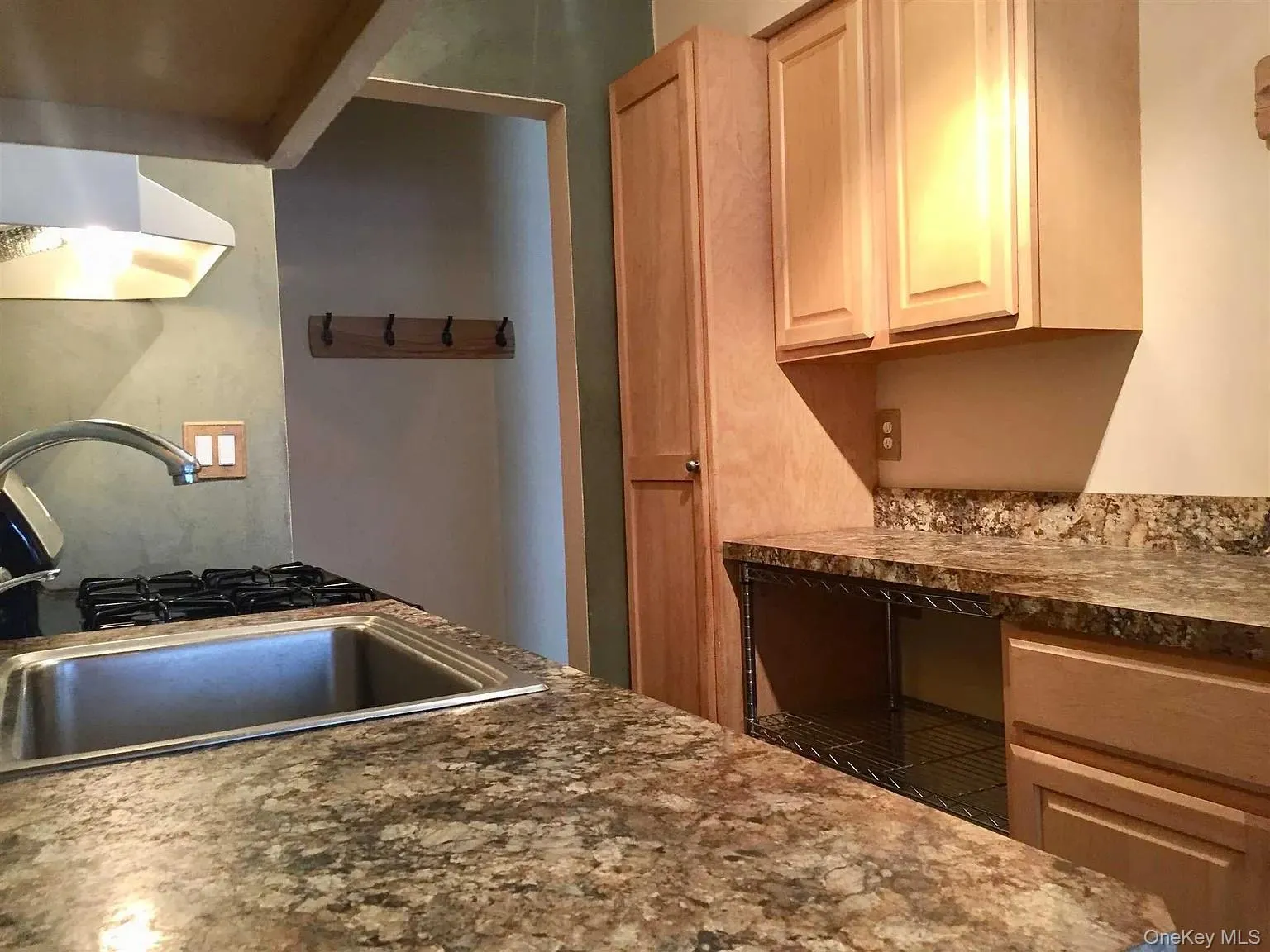 Kitchen featuring dark countertops and under cabinet range hood Kitchen featuring dark countertops and under cabinet range hood