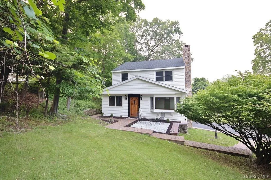 View of front facade with a chimney, a front yard, and covered porch View of front facade with a chimney, a front yard, and covered porch