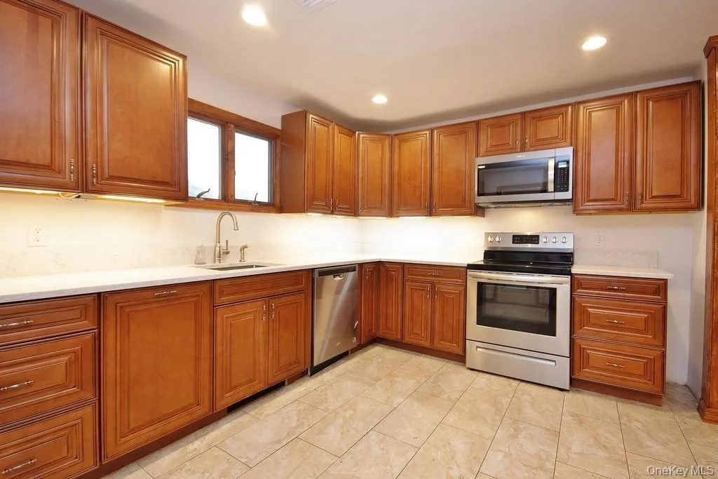 Kitchen with stainless steel appliances, brown cabinetry, and recessed lighting Kitchen with stainless steel appliances, brown cabinetry, and recessed lighting
