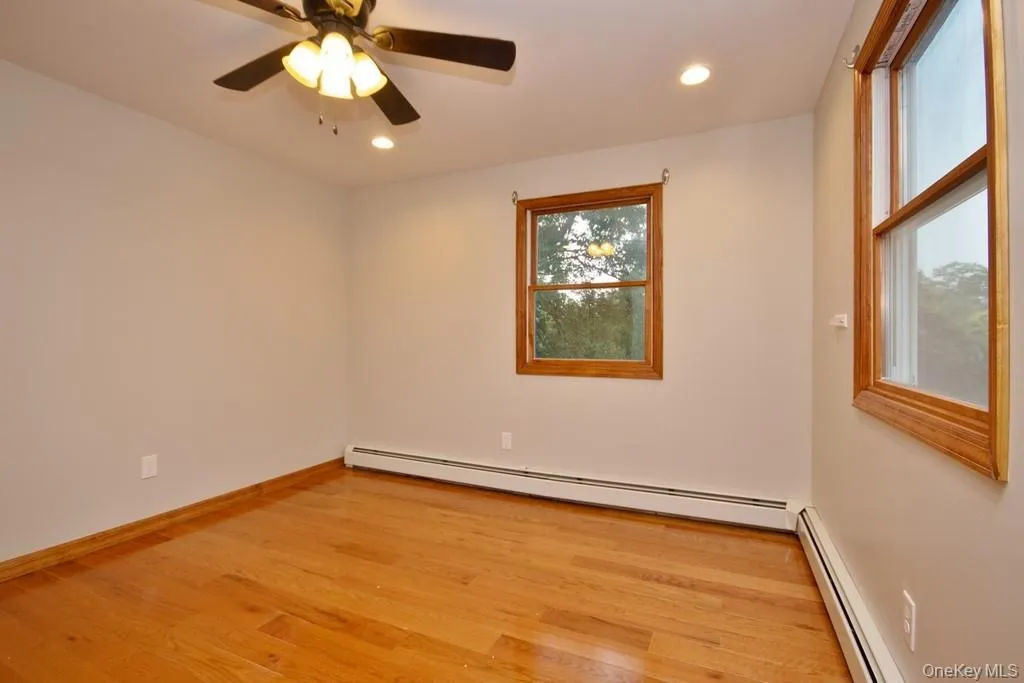 Empty room with light wood-style floors, a baseboard radiator, and recessed lighting Empty room with light wood-style floors, a baseboard radiator, and recessed lighting