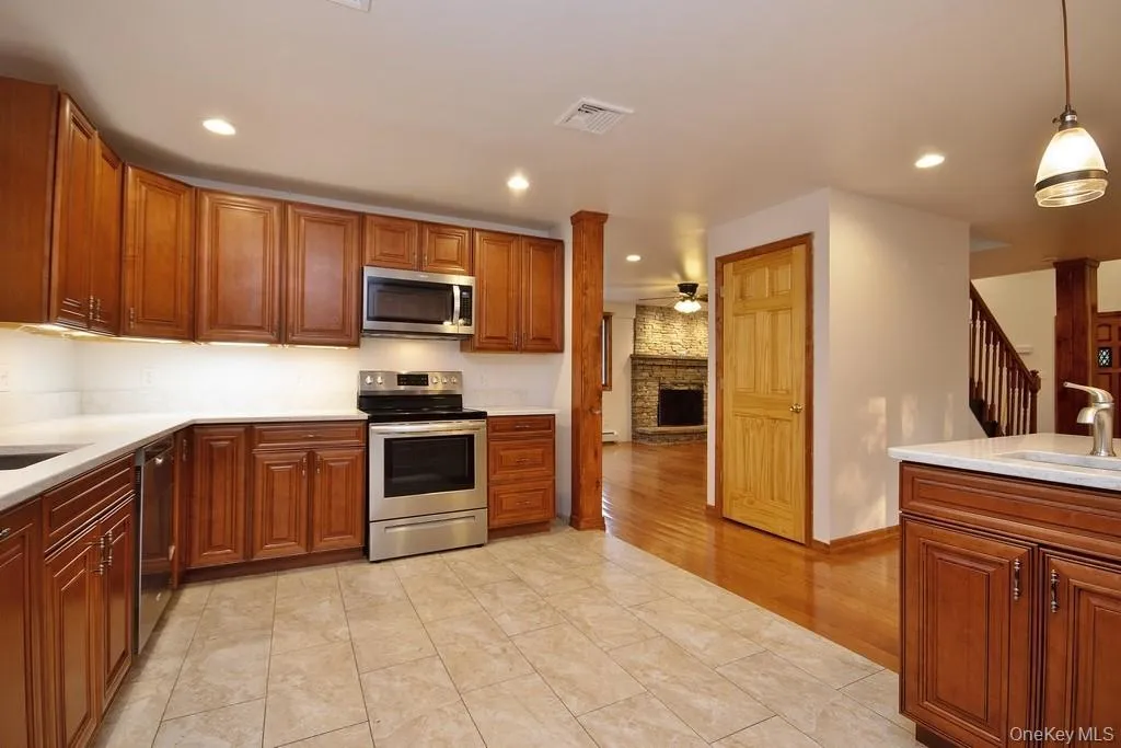 Kitchen with stainless steel appliances, hanging light fixtures, ceiling fan, light stone countertops, and recessed lighting Kitchen with stainless steel appliances, hanging light fixtures, ceiling fan, light stone countertops, and recessed lighting