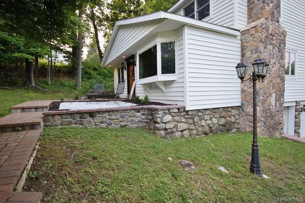 View of home's exterior featuring a yard and stone siding View of home's exterior featuring a yard and stone siding