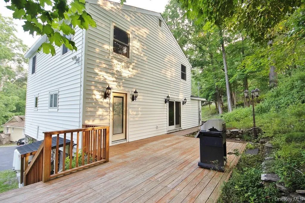 Wooden deck featuring a grill and view of scattered trees Wooden deck featuring a grill and view of scattered trees