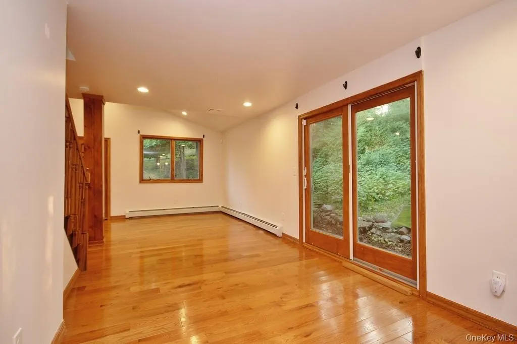 Spare room featuring light wood finished floors, recessed lighting, lofted ceiling, and a baseboard radiator Spare room featuring light wood finished floors, recessed lighting, lofted ceiling, and a baseboard radiator