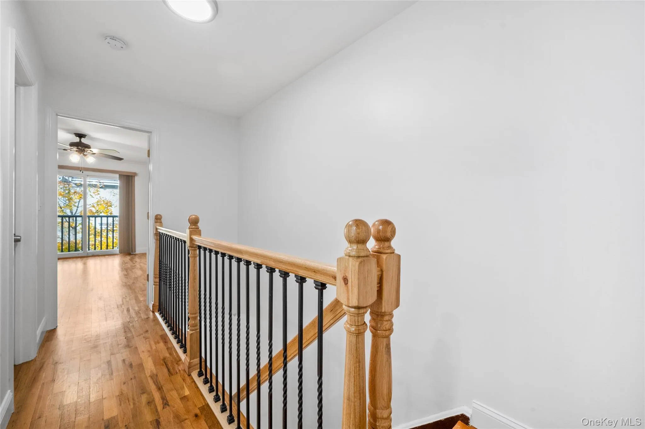 Hall featuring an upstairs landing and wood finished floors Hall featuring an upstairs landing and wood finished floors