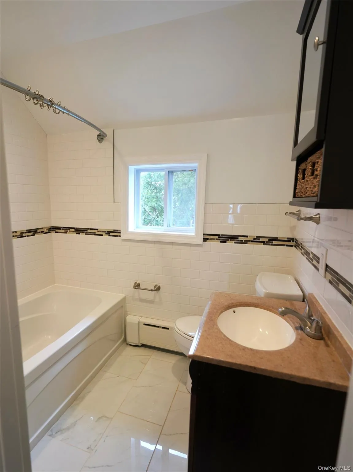 Full bathroom with tile walls, vanity, light marble finish flooring, shower / bathtub combination, and a baseboard radiator Full bathroom with tile walls, vanity, light marble finish flooring, shower / bathtub combination, and a baseboard radiator
