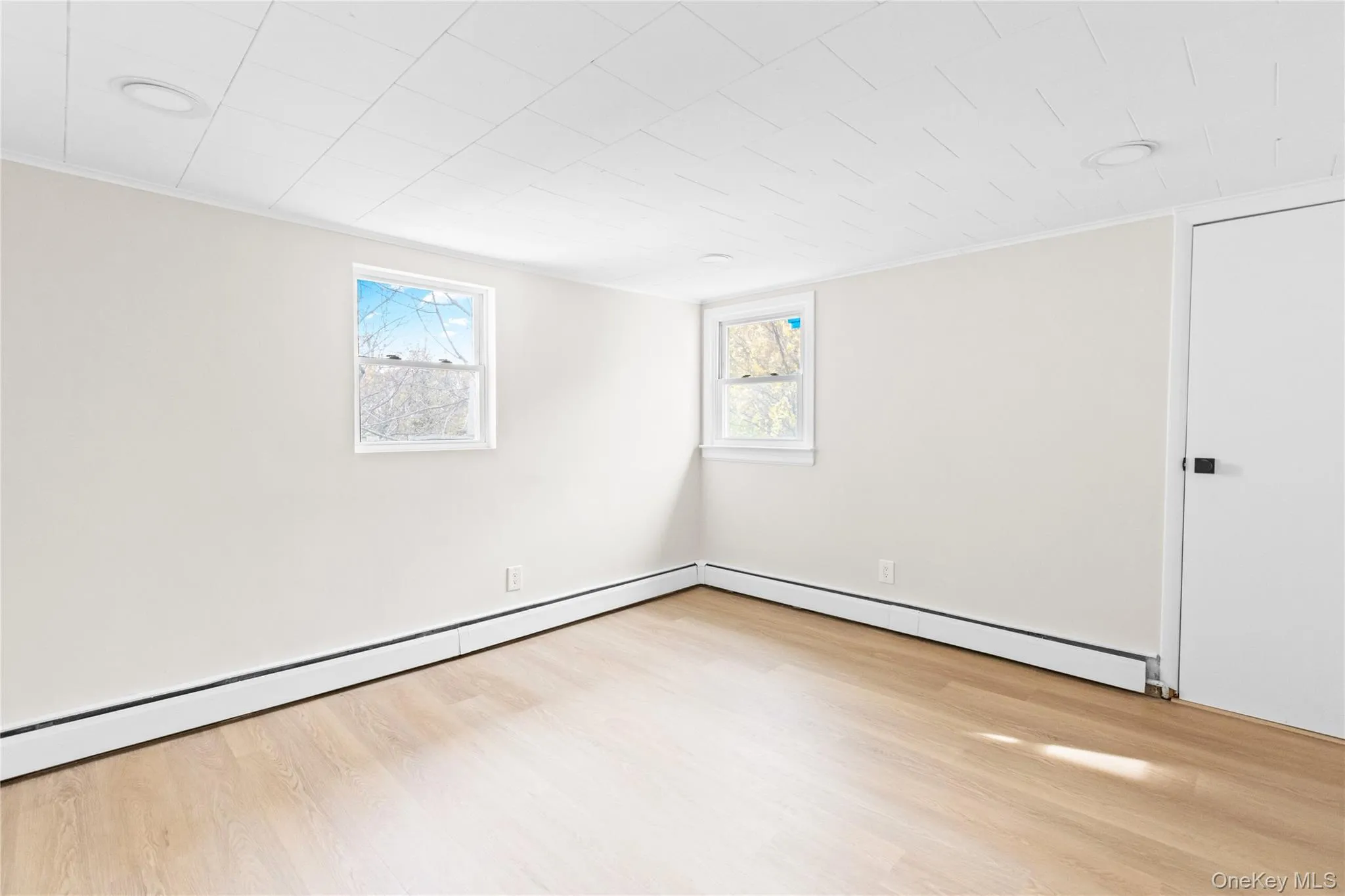 Empty room featuring light wood-style flooring and a baseboard radiator Empty room featuring light wood-style flooring and a baseboard radiator