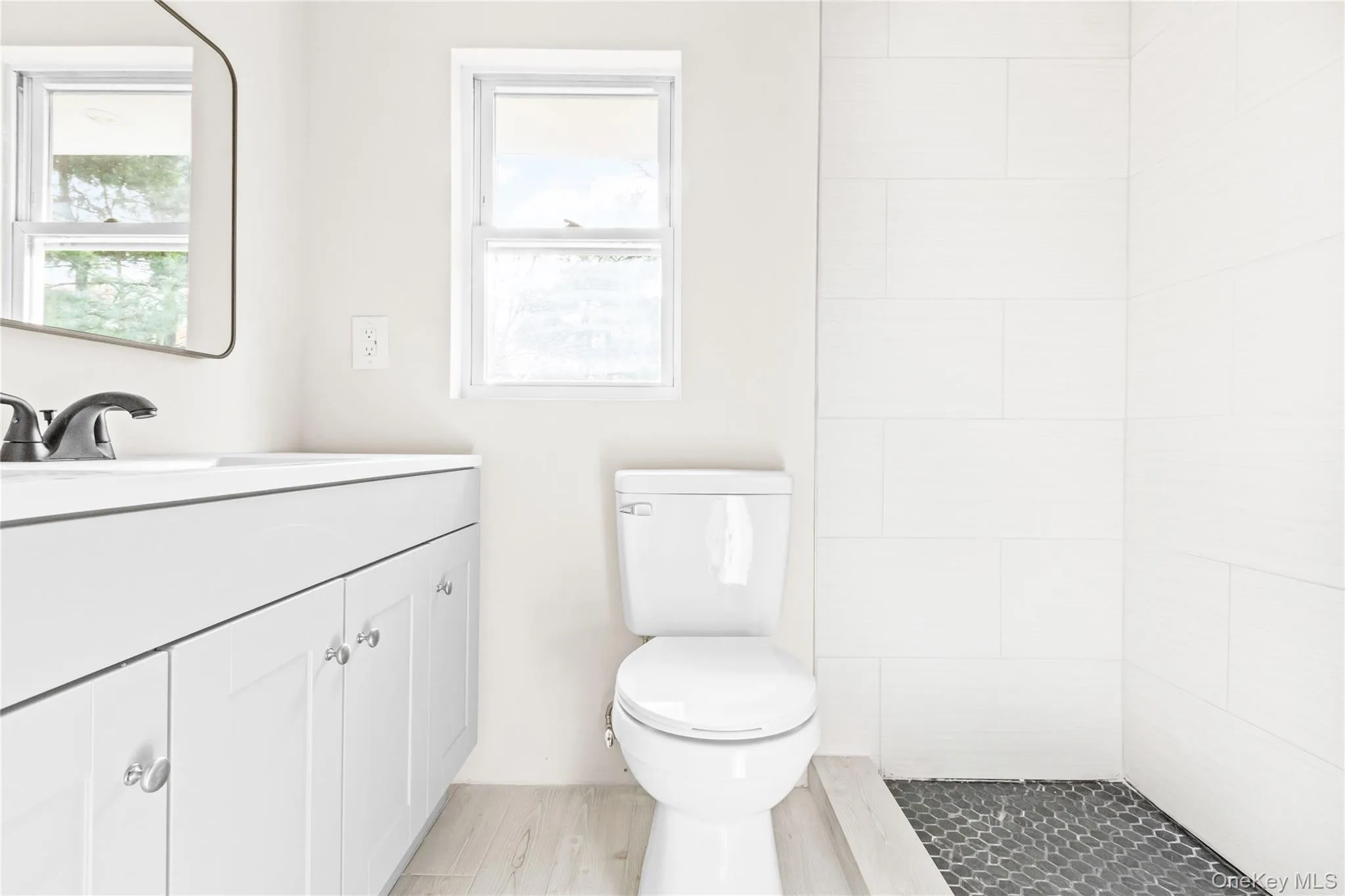 Bathroom with vanity, a tile shower, and light wood finished floors Bathroom with vanity, a tile shower, and light wood finished floors