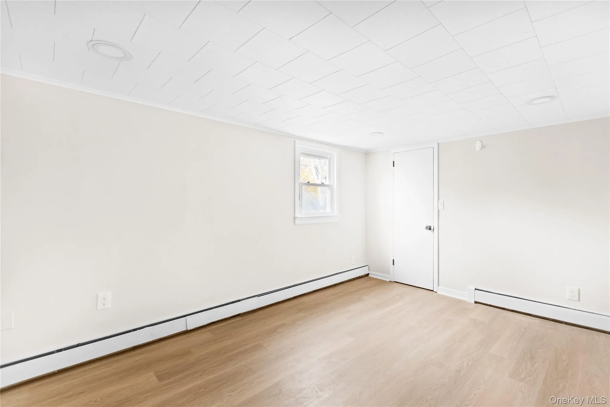 Spare room with baseboard heating and light wood-type flooring Spare room with baseboard heating and light wood-type flooring