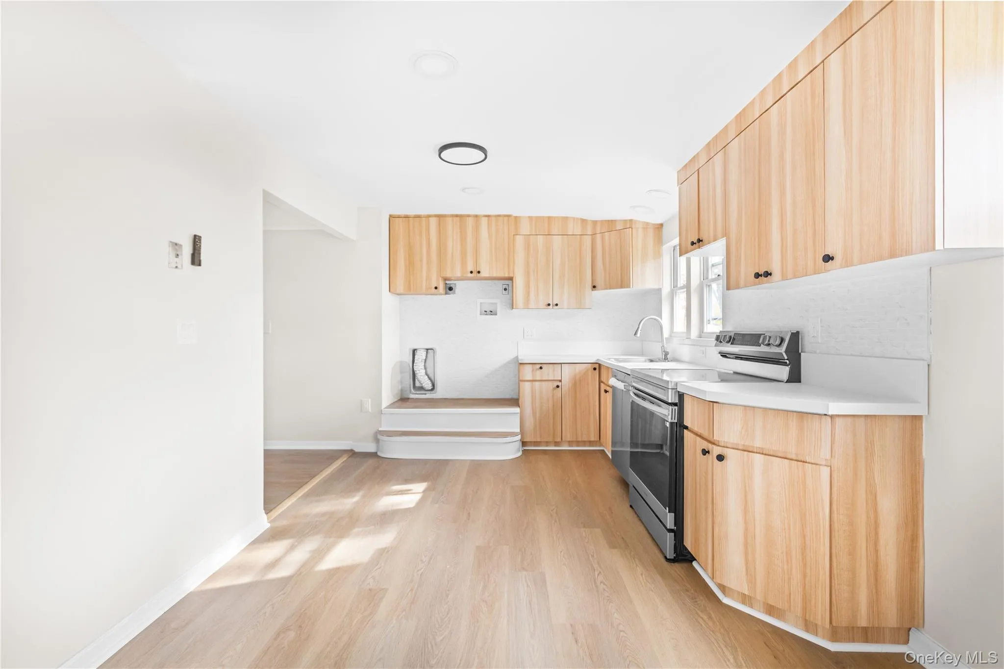 Kitchen featuring light brown cabinets, stainless steel appliances, modern cabinets, light countertops, and light wood-style flooring Kitchen featuring light brown cabinets, stainless steel appliances, modern cabinets, light countertops, and light wood-style flooring