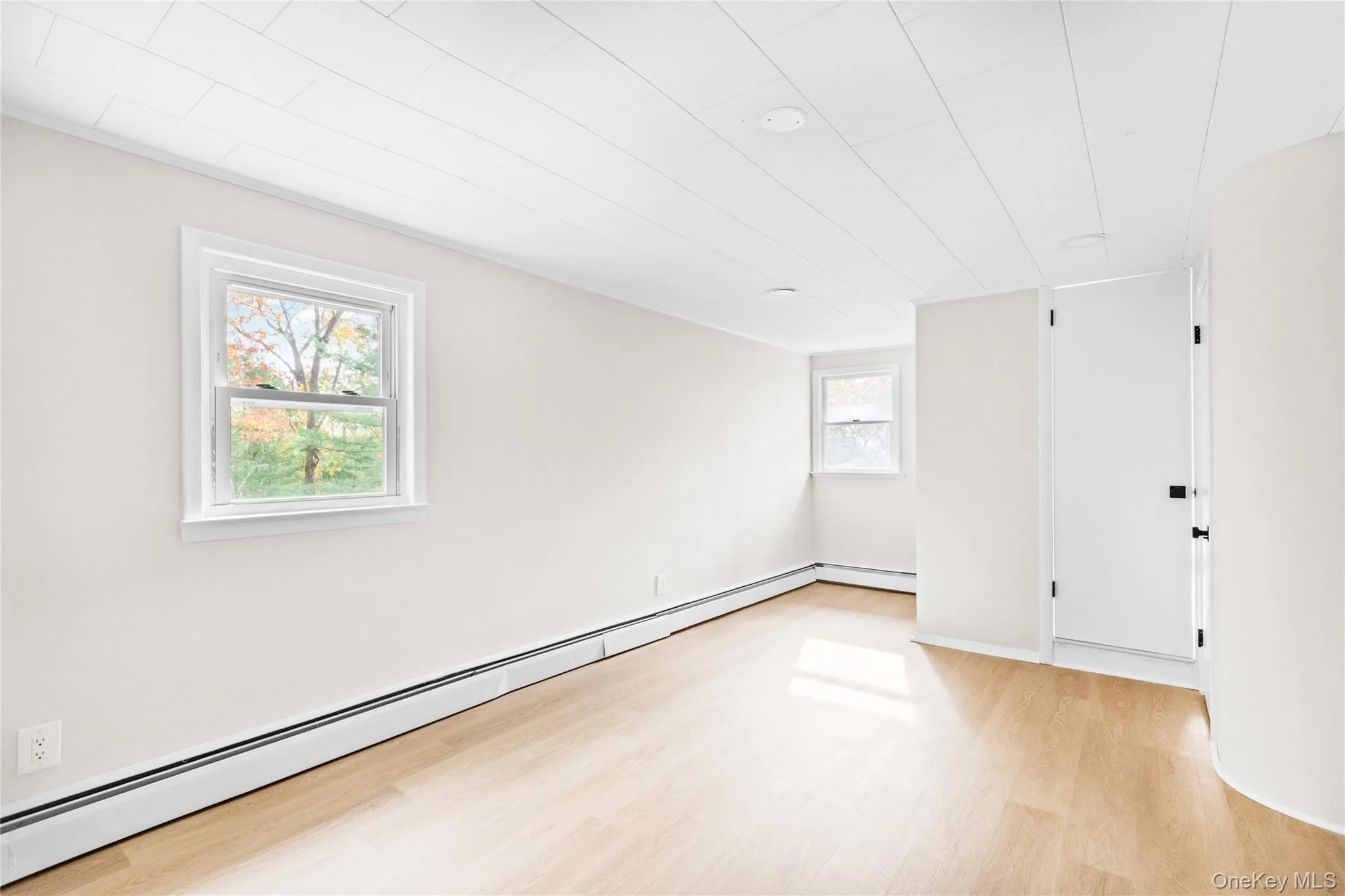 Unfurnished room featuring a baseboard heating unit and light wood-style floors Unfurnished room featuring a baseboard heating unit and light wood-style floors