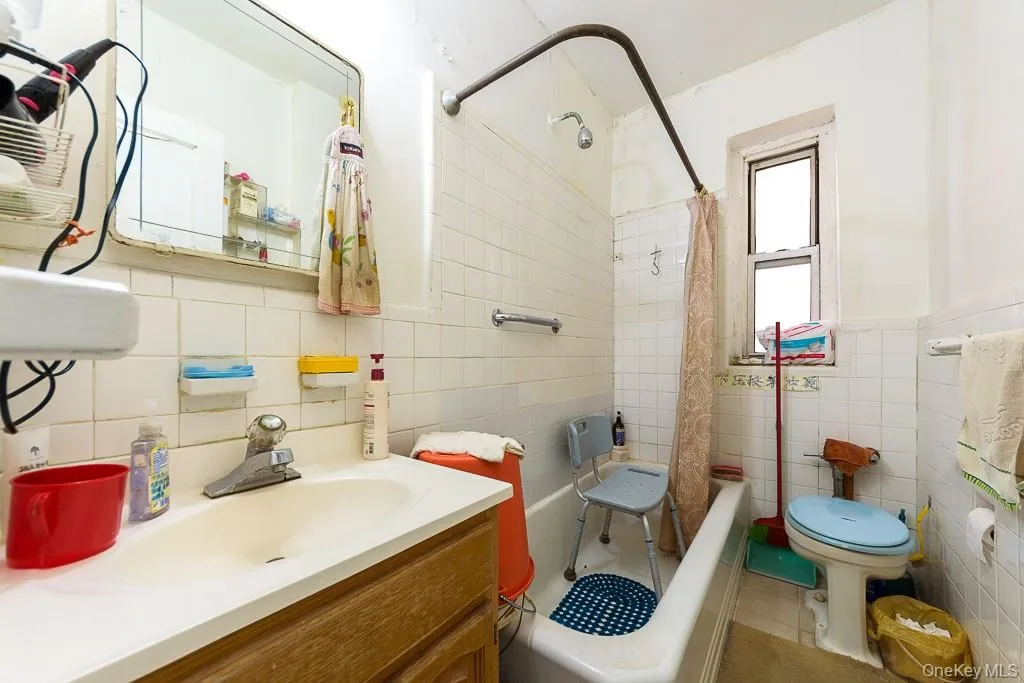 Full bath featuring vanity, shower / bath combo with shower curtain, tile walls, and tile patterned floors Full bath featuring vanity, shower / bath combo with shower curtain, tile walls, and tile patterned floors