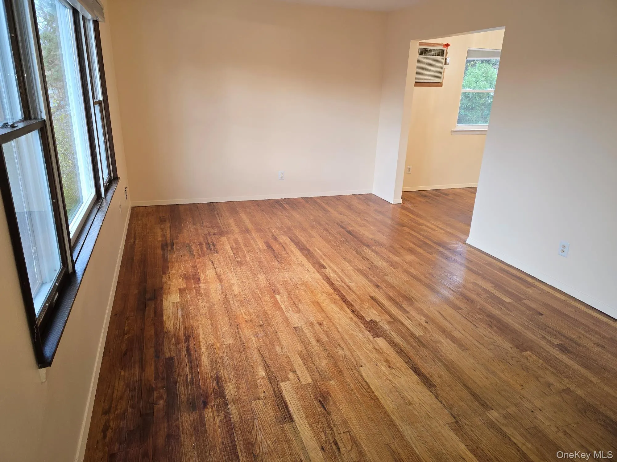 Unfurnished room with dark wood-type flooring and an AC wall unit Unfurnished room with dark wood-type flooring and an AC wall unit