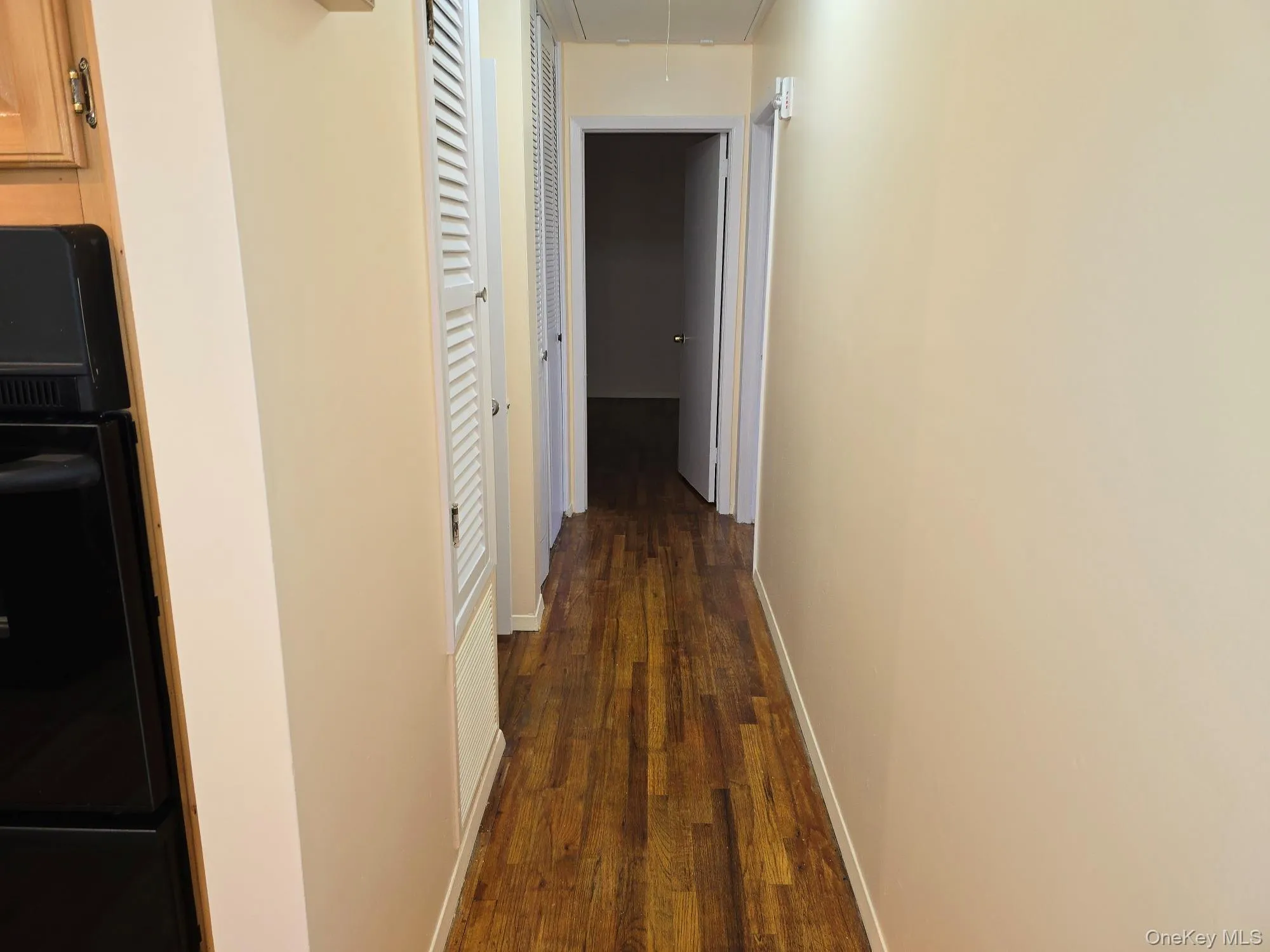 Hall featuring attic access and dark wood finished floors Hall featuring attic access and dark wood finished floors
