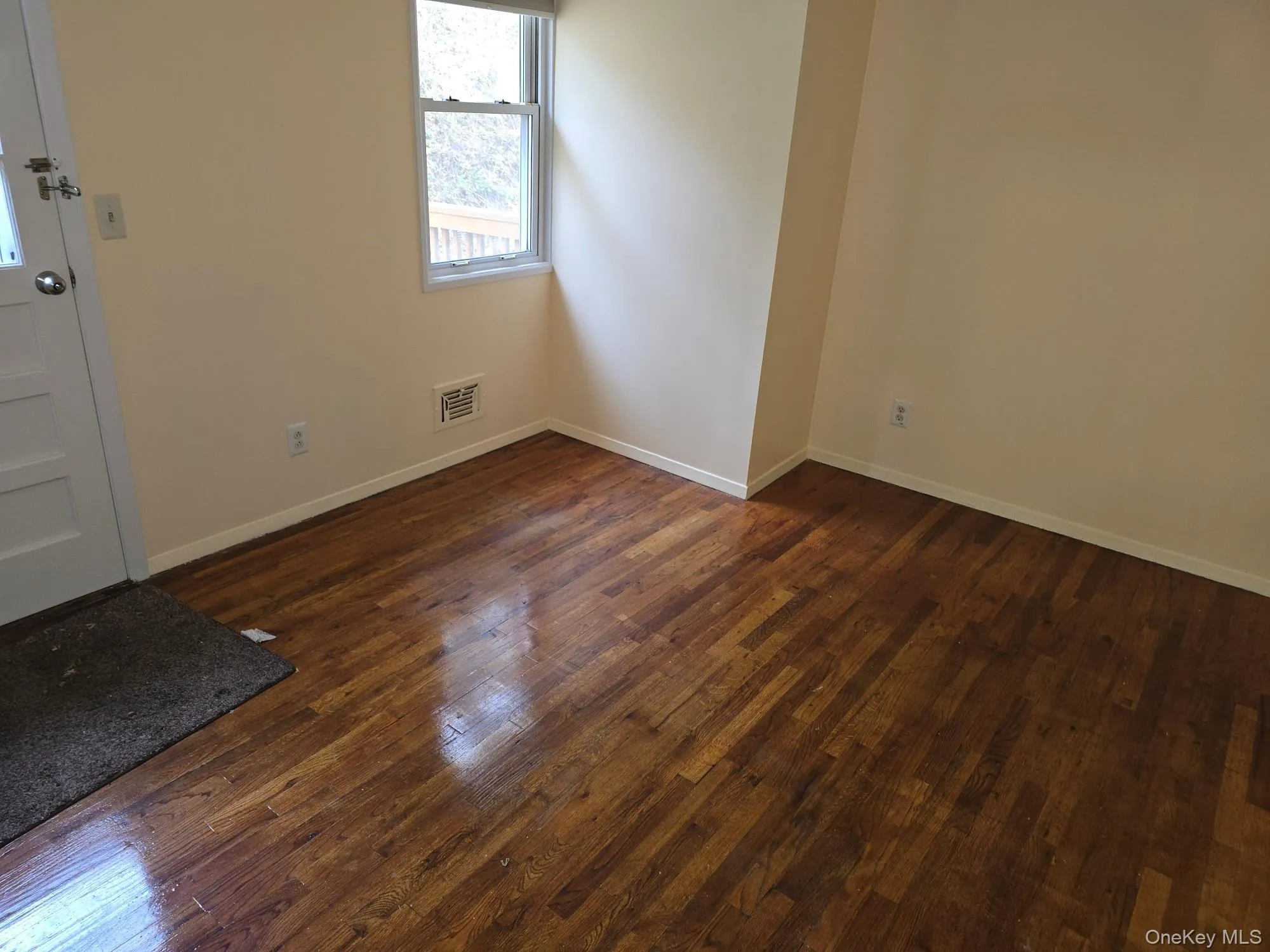 Empty room with dark wood-type flooring and baseboards Empty room with dark wood-type flooring and baseboards