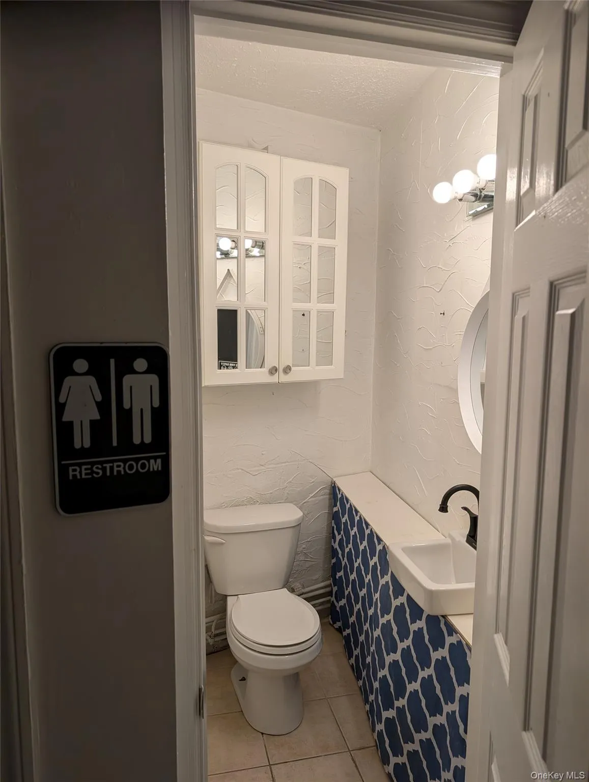 Bathroom featuring a textured wall and light tile patterned flooring Bathroom featuring a textured wall and light tile patterned flooring