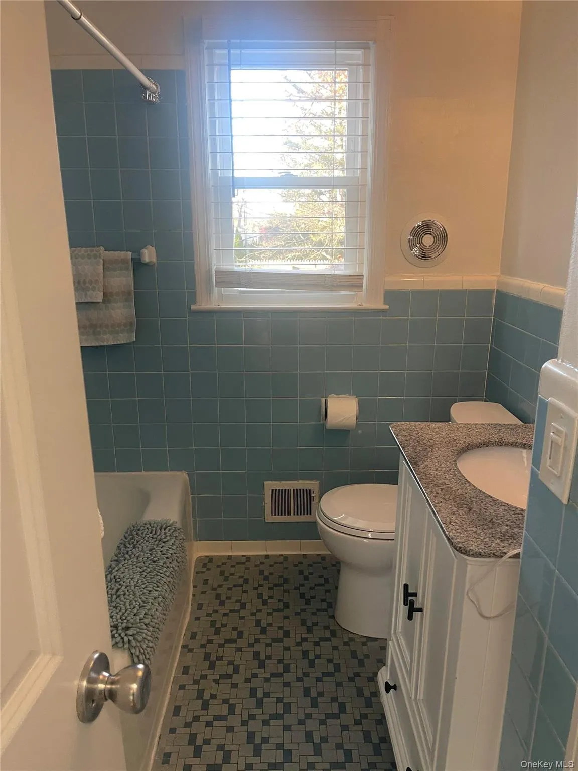 Full bath with vanity, tile walls, and dark tile patterned floors Full bath with vanity, tile walls, and dark tile patterned floors
