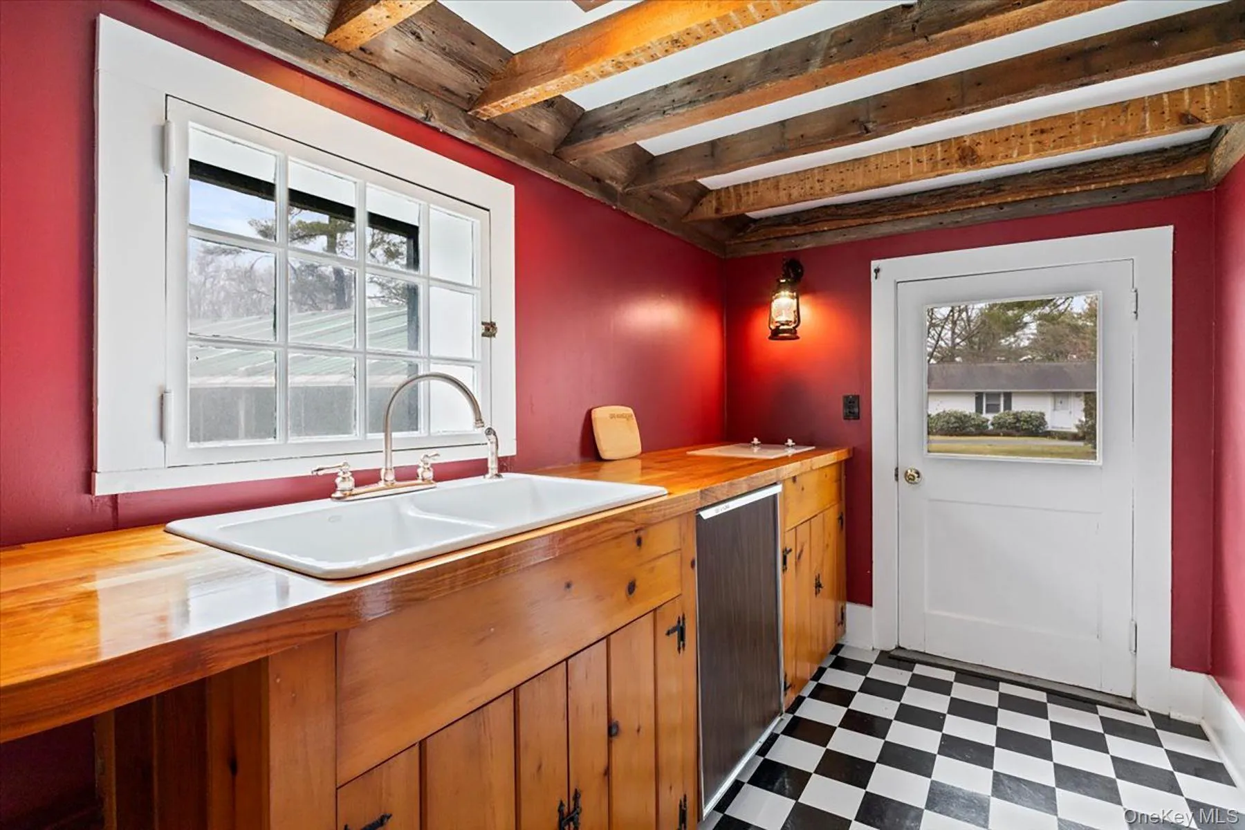 Kitchen featuring dark floors, wooden counters, beamed ceiling, dishwasher, and brown cabinets Kitchen featuring dark floors, wooden counters, beamed ceiling, dishwasher, and brown cabinets