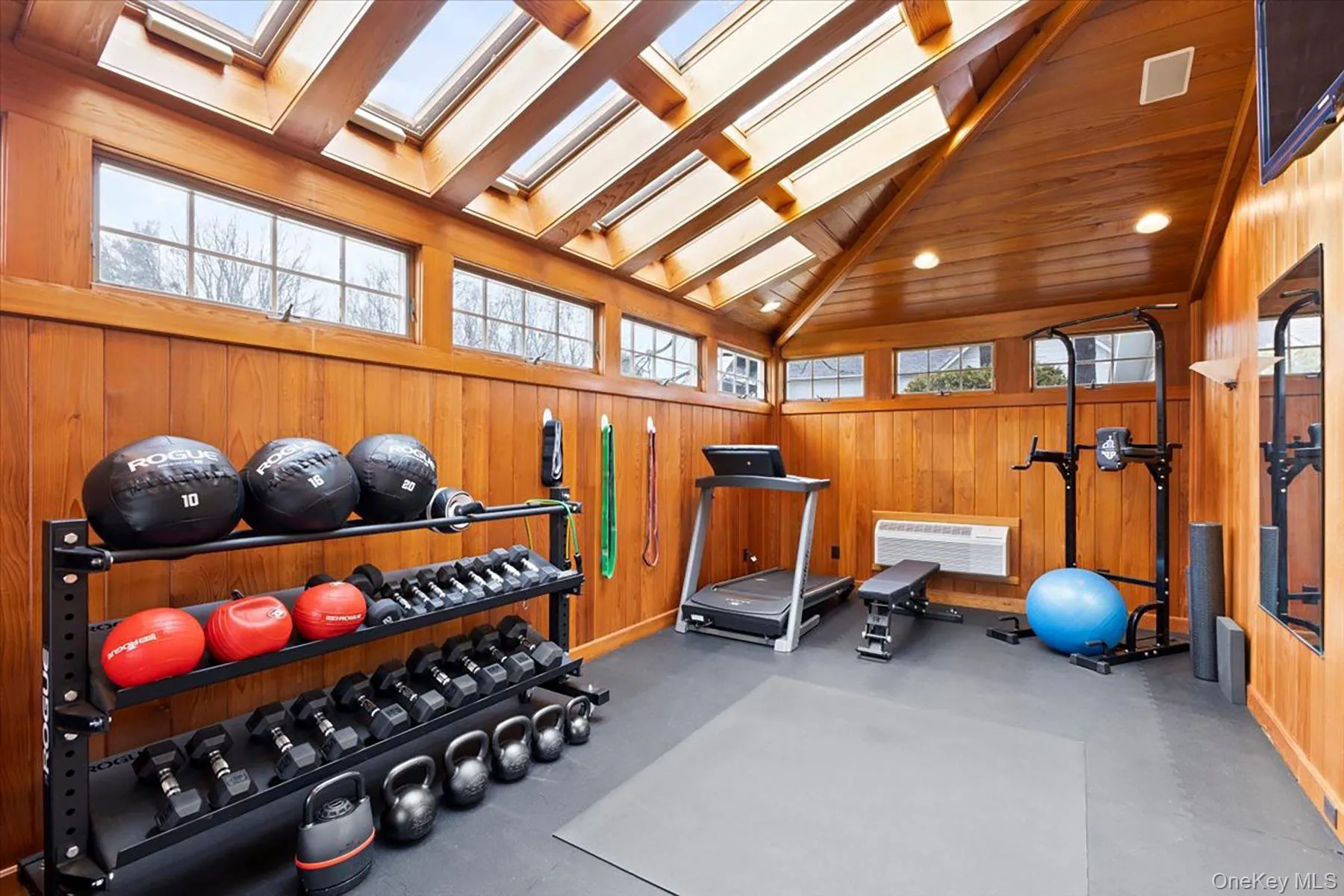 Workout area with wooden walls, high vaulted ceiling, a wall mounted AC, and a skylight Workout area with wooden walls, high vaulted ceiling, a wall mounted AC, and a skylight