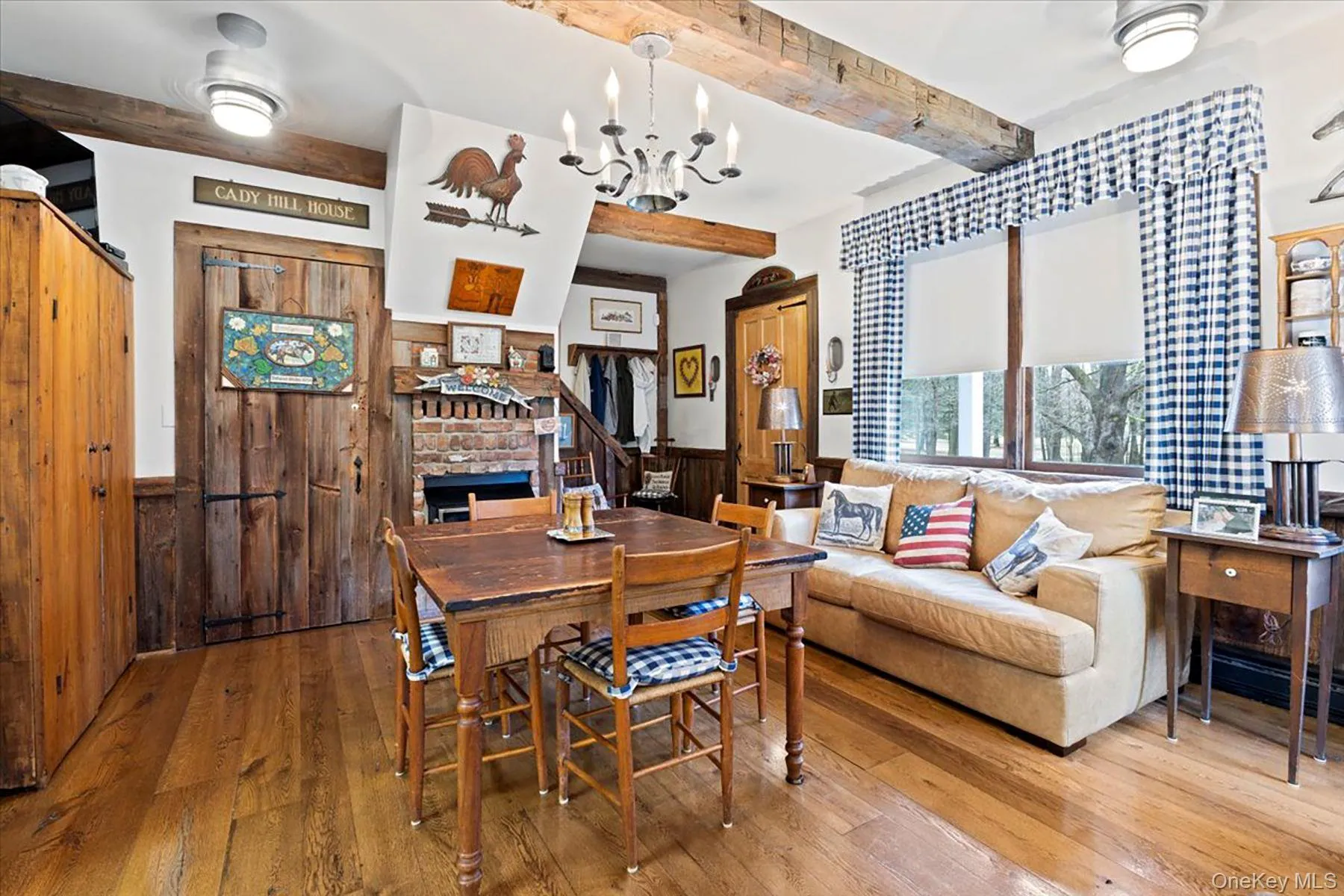 Dining space featuring beamed ceiling, wooden walls, hardwood / wood-style flooring, a wainscoted wall, and a chandelier Dining space featuring beamed ceiling, wooden walls, hardwood / wood-style flooring, a wainscoted wall, and a chandelier
