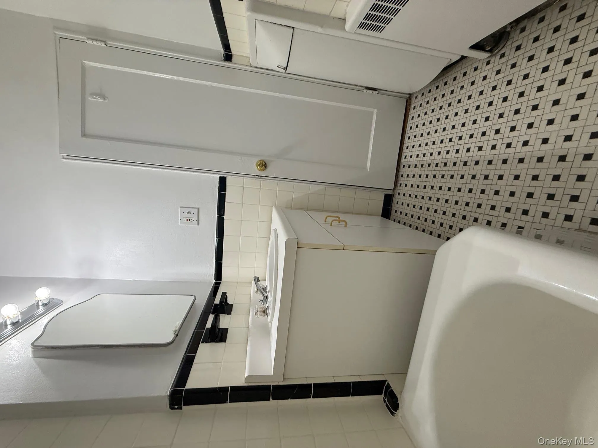 Bathroom with tile walls, a tub, a wainscoted wall, vanity, and radiator Bathroom with tile walls, a tub, a wainscoted wall, vanity, and radiator