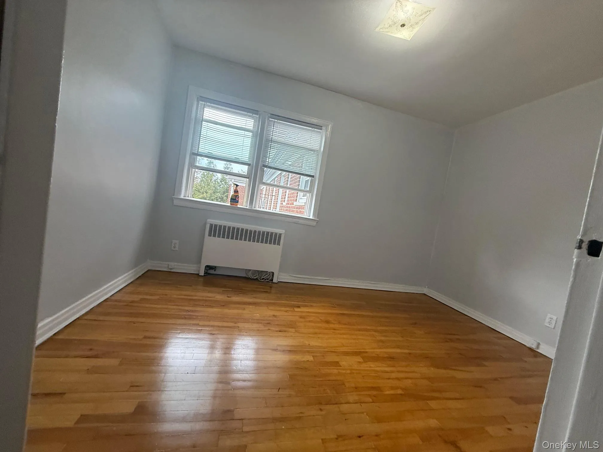 Empty room featuring radiator and light wood-style flooring Empty room featuring radiator and light wood-style flooring