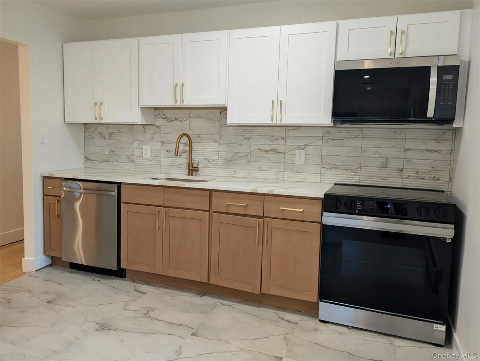Kitchen with stainless steel appliances, backsplash, light marble finish flooring, white cabinetry, and light stone countertops Kitchen with stainless steel appliances, backsplash, light marble finish flooring, white cabinetry, and light stone countertops