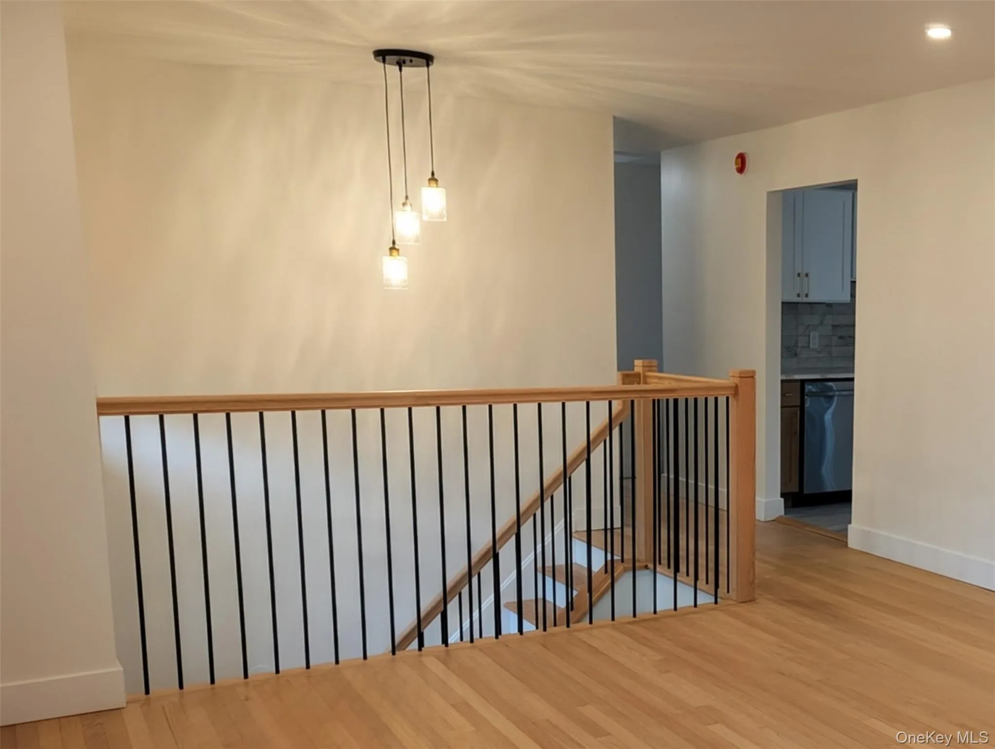 Hallway featuring an upstairs landing, light wood finished floors, and recessed lighting Hallway featuring an upstairs landing, light wood finished floors, and recessed lighting