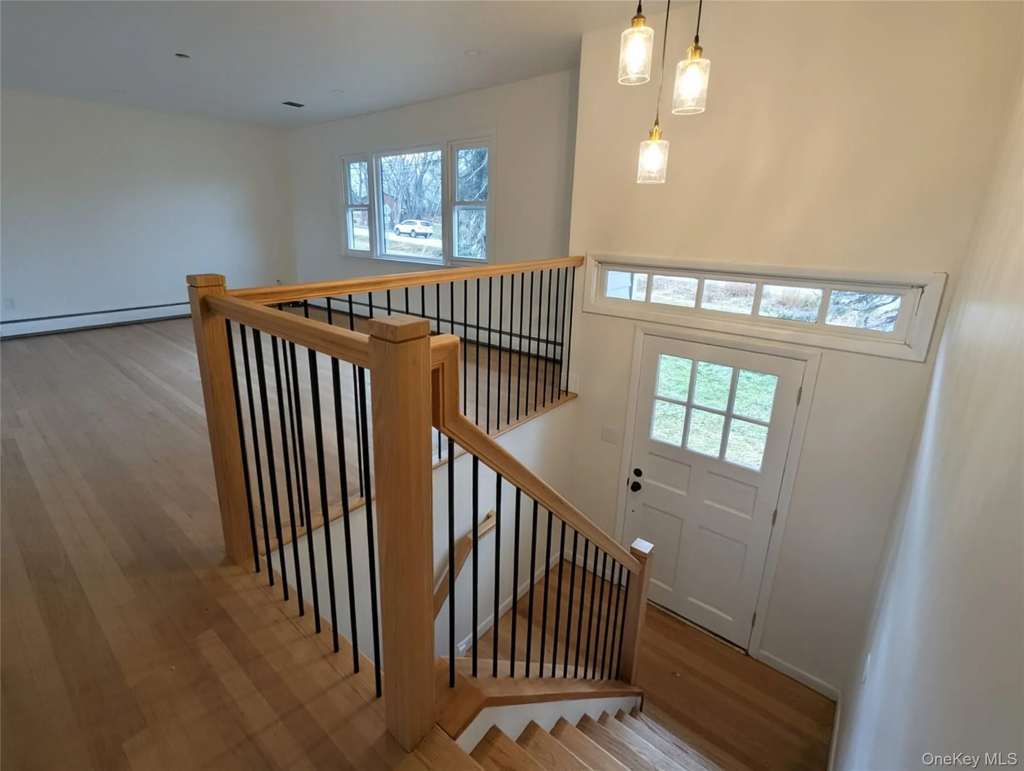 Staircase featuring wood finished floors, baseboard heating, a baseboard heating unit, and a high ceiling Staircase featuring wood finished floors, baseboard heating, a baseboard heating unit, and a high ceiling