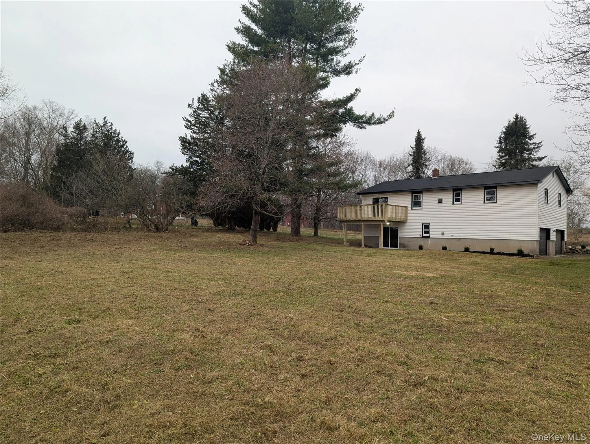 View of green lawn featuring a wooden deck View of green lawn featuring a wooden deck
