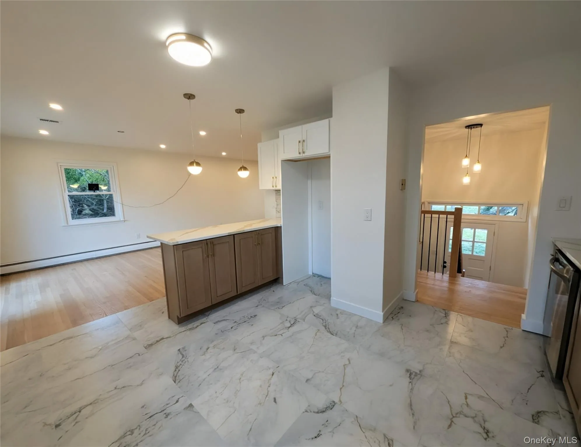 Kitchen with light marble finish floors, pendant lighting, baseboard heating, light countertops, and stainless steel dishwasher Kitchen with light marble finish floors, pendant lighting, baseboard heating, light countertops, and stainless steel dishwasher