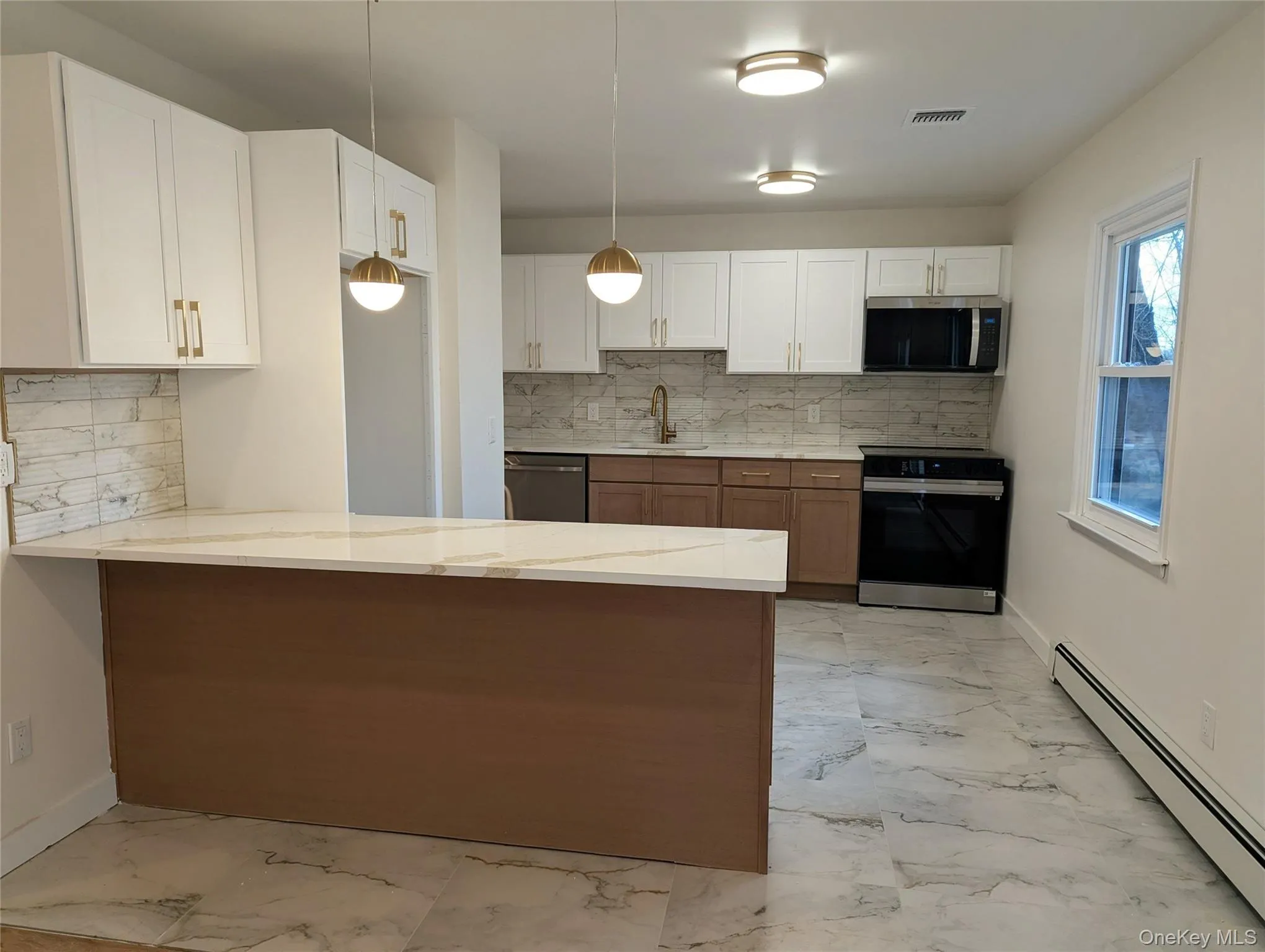 Kitchen with a baseboard radiator, brown cabinetry, white cabinetry, stainless steel appliances, and backsplash Kitchen with a baseboard radiator, brown cabinetry, white cabinetry, stainless steel appliances, and backsplash