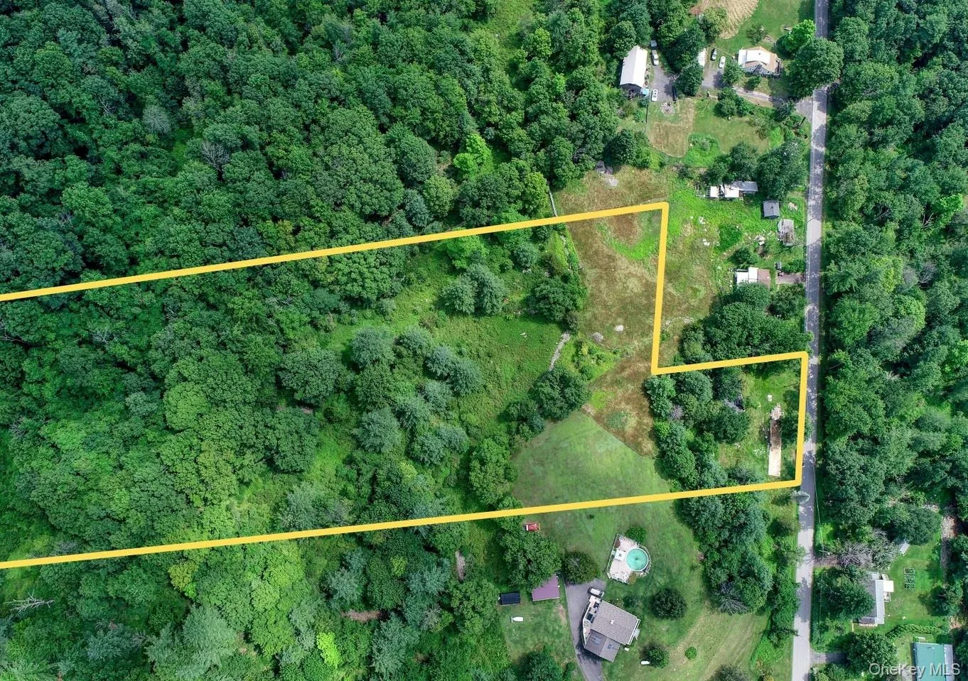 Aerial view of property and surrounding area featuring a heavily wooded area and property parcel outlined Aerial view of property and surrounding area featuring a heavily wooded area and property parcel outlined