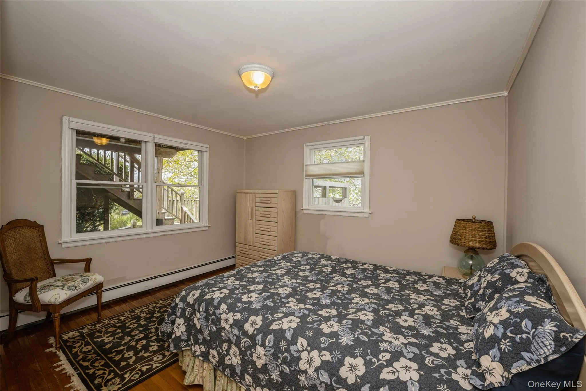 Bedroom featuring dark wood-style flooring, crown molding, and a baseboard heating unit Bedroom featuring dark wood-style flooring, crown molding, and a baseboard heating unit