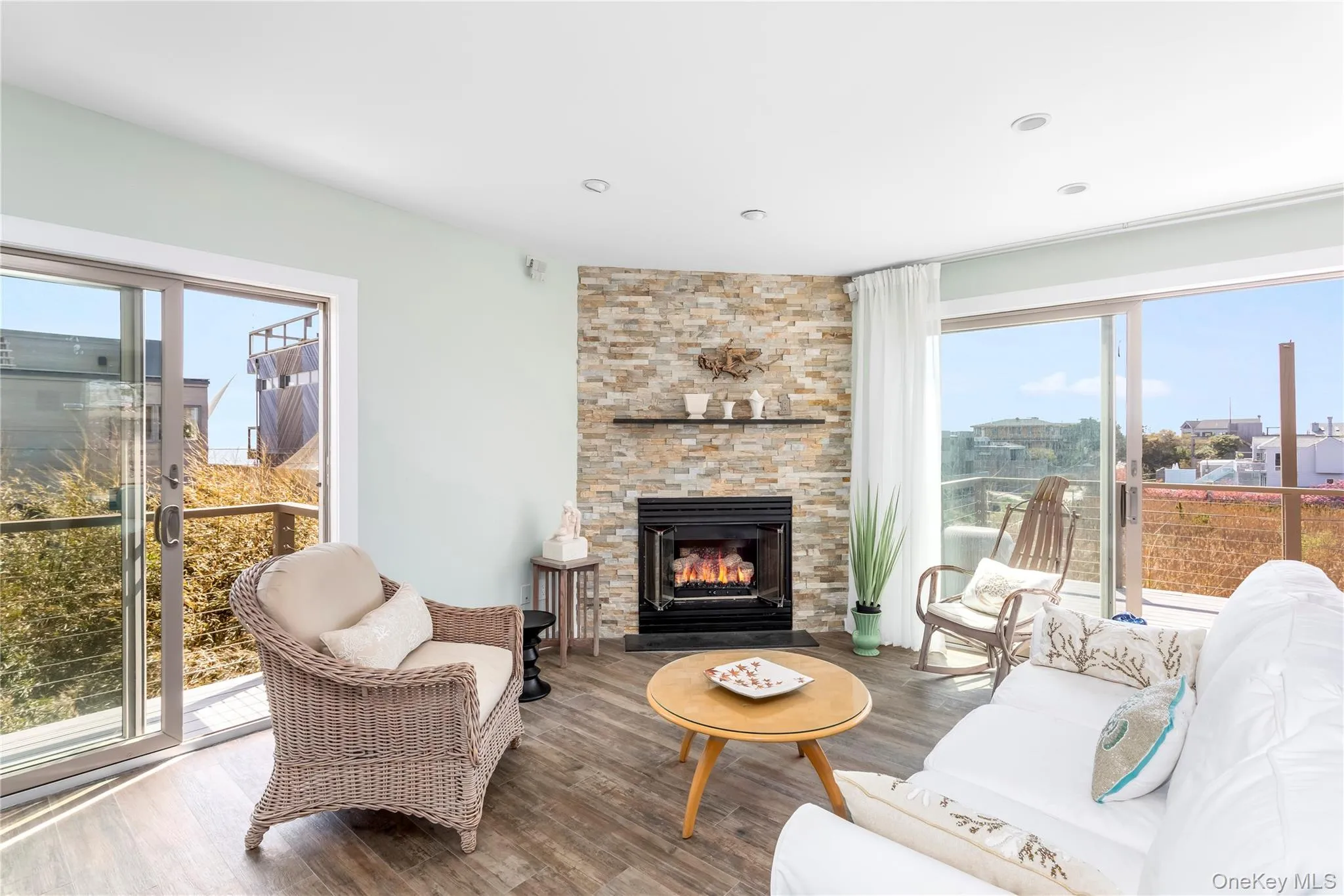 Living area with wood finished floors, a stone fireplace, and recessed lighting Living area with wood finished floors, a stone fireplace, and recessed lighting