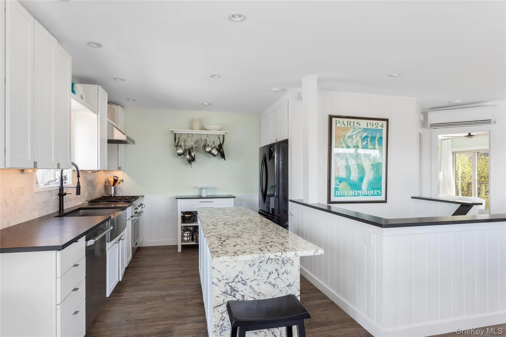Kitchen featuring white cabinetry, a kitchen island, dark wood-style floors, recessed lighting, and wooden walls Kitchen featuring white cabinetry, a kitchen island, dark wood-style floors, recessed lighting, and wooden walls