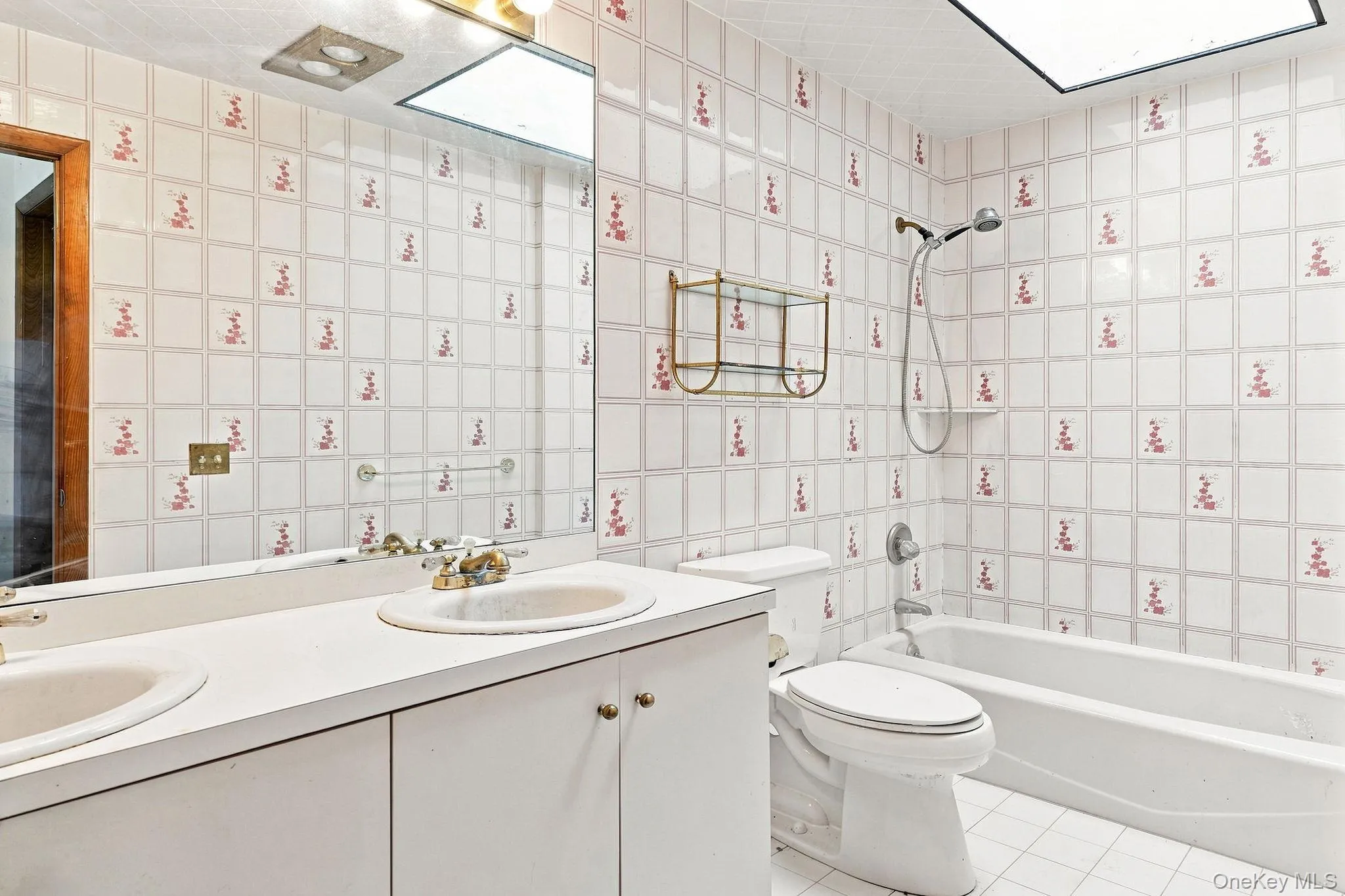 Dual vanity with integrated sinks, full-width mirror, tile flooring, and a bathtub with shower Dual vanity with integrated sinks, full-width mirror, tile flooring, and a bathtub with shower