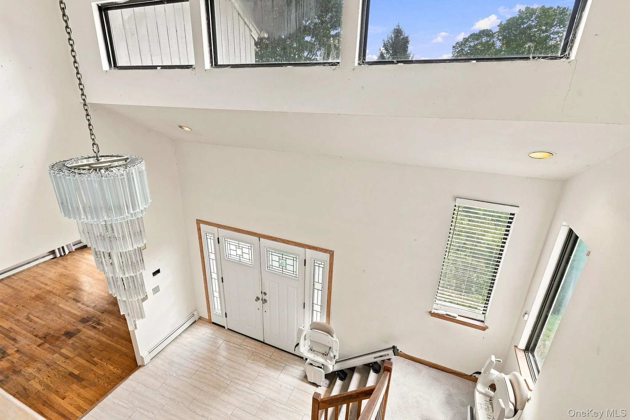 Two-story entry featuring a tiered chandelier, dual entry doors with decorative glass panels, and multiple skylights Two-story entry featuring a tiered chandelier, dual entry doors with decorative glass panels, and multiple skylights