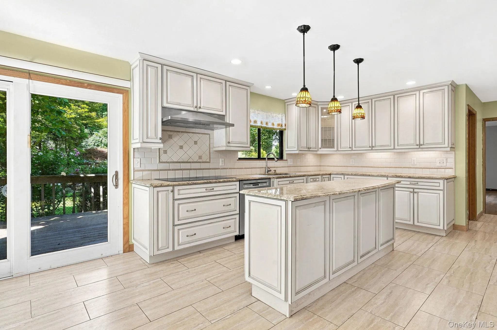 White cabinetry with decorative trim, durable tile flooring, granite countertops, tile backsplash, and a central island White cabinetry with decorative trim, durable tile flooring, granite countertops, tile backsplash, and a central island