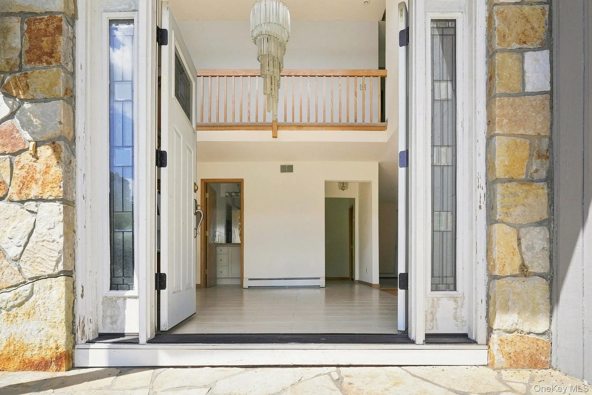 Two-story foyer with a decorative chandelier and a wood-finish railing Two-story foyer with a decorative chandelier and a wood-finish railing