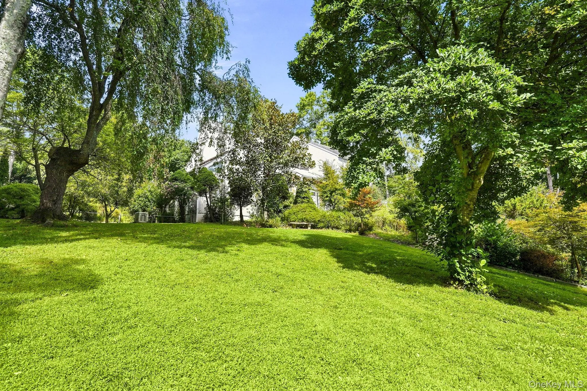 Expansive lawn with mature trees and a white-sided residence Expansive lawn with mature trees and a white-sided residence